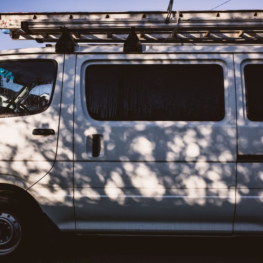 White tradesman van with roof-rack ladder on a quiet street