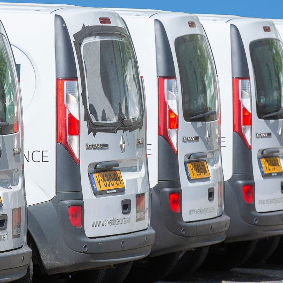 Multiple white delivery vans parked in a neat row