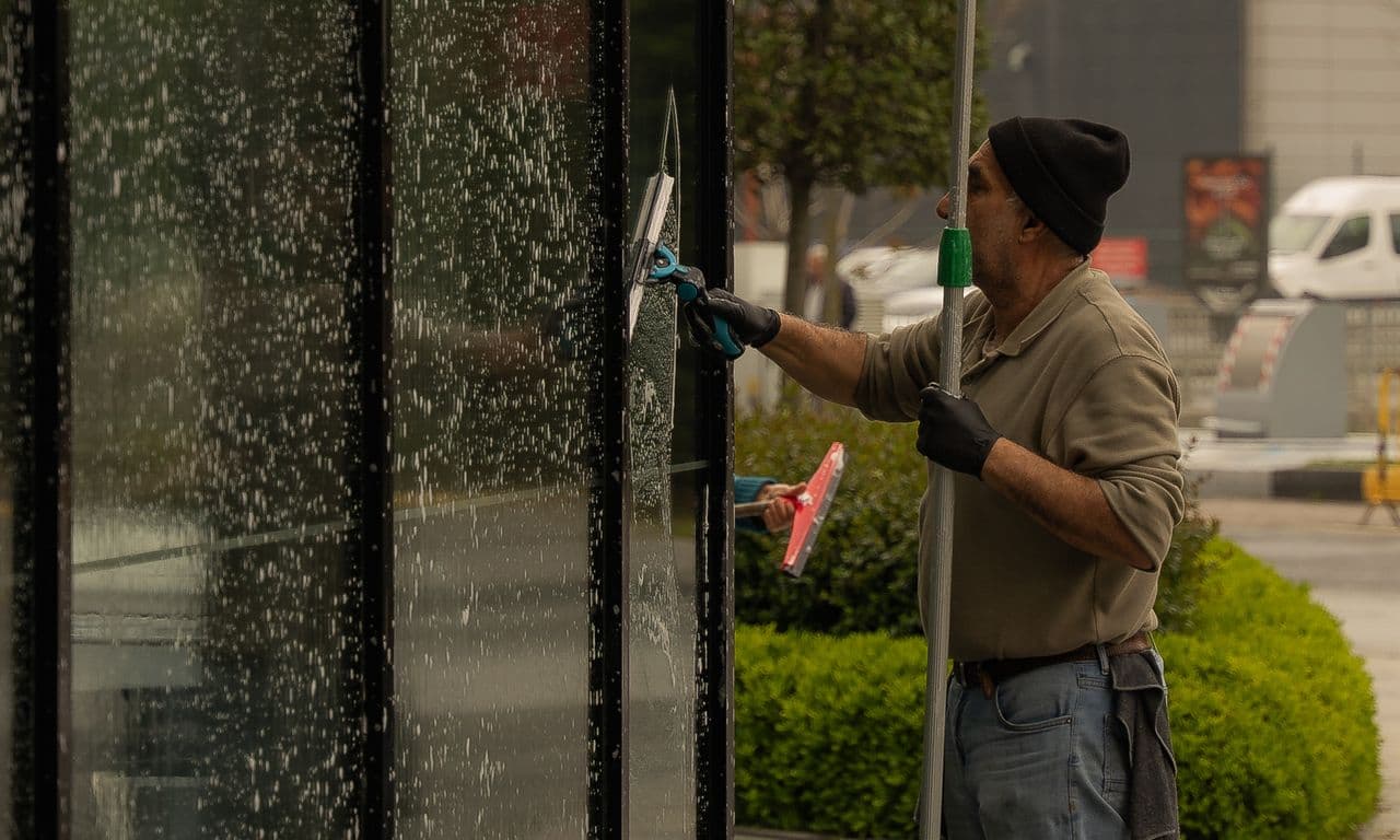 Window cleaner dragging a squeegee down clean glass